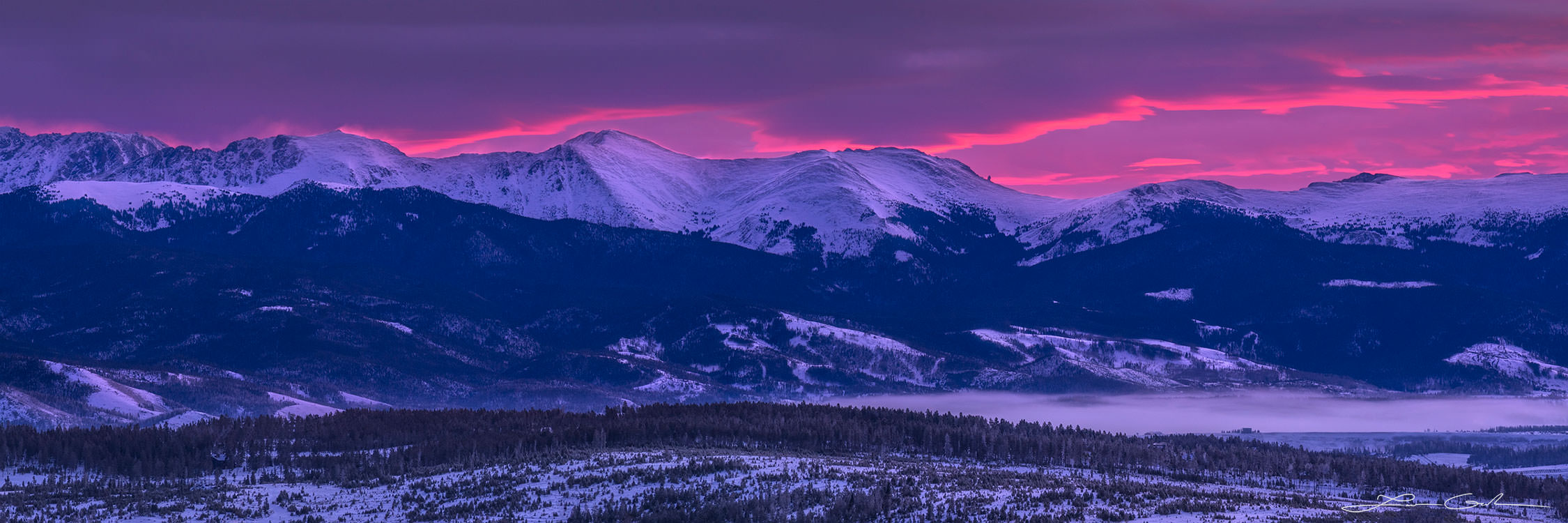 Dramatic red winter sunrise over snow covered mountains and Colorado Fraser Valley