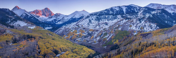 Big mountain valley with yellow aspens, fresh snow and a sunset on Capitol Peak