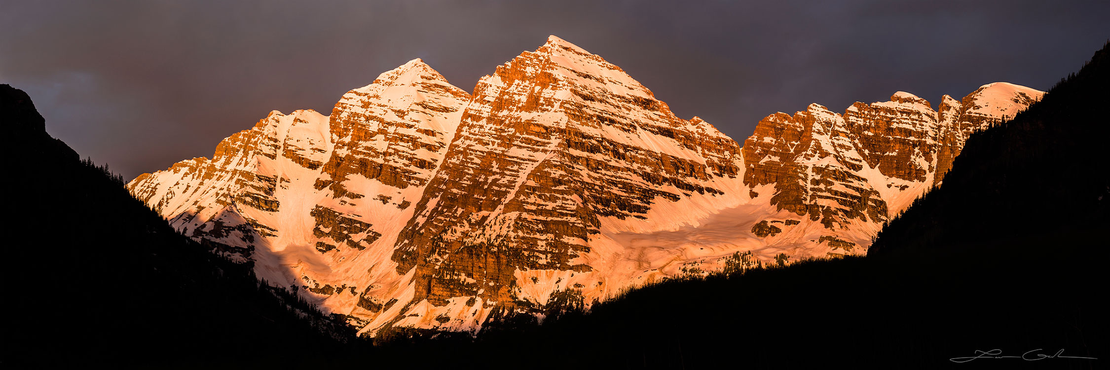 Beautiful Maroonbells snow covered mountains illuminated by orange sunrise light