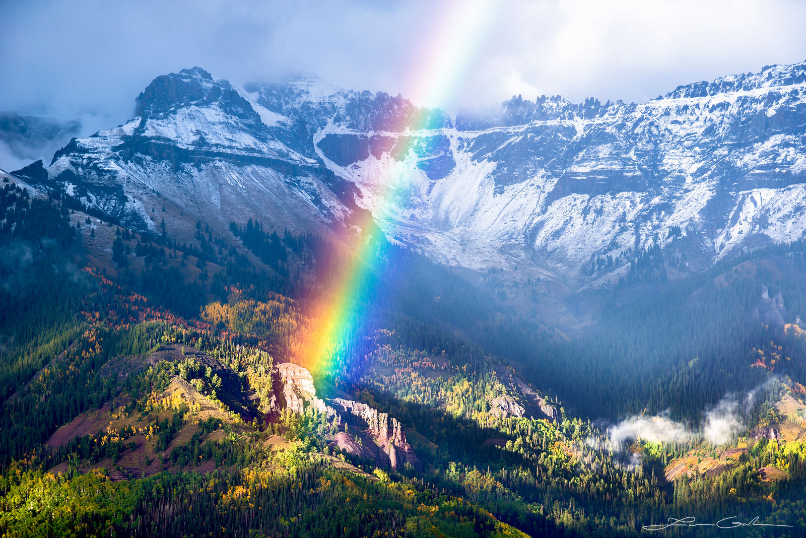 Beautiful mountain rainbow over yellow aspens and snow covered mountains in Telluride