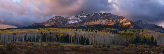 Wilson Peak, Colorado in morning light with clouds above and yellow aspens below