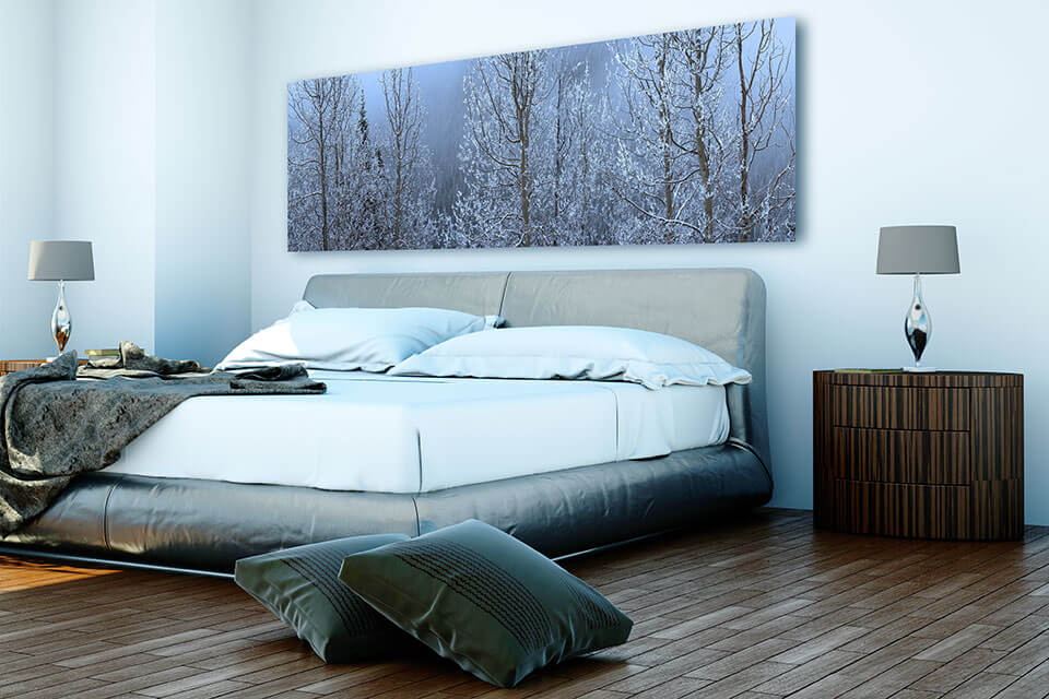 A panoramic print of winter trees above a bedroom bed interior design
