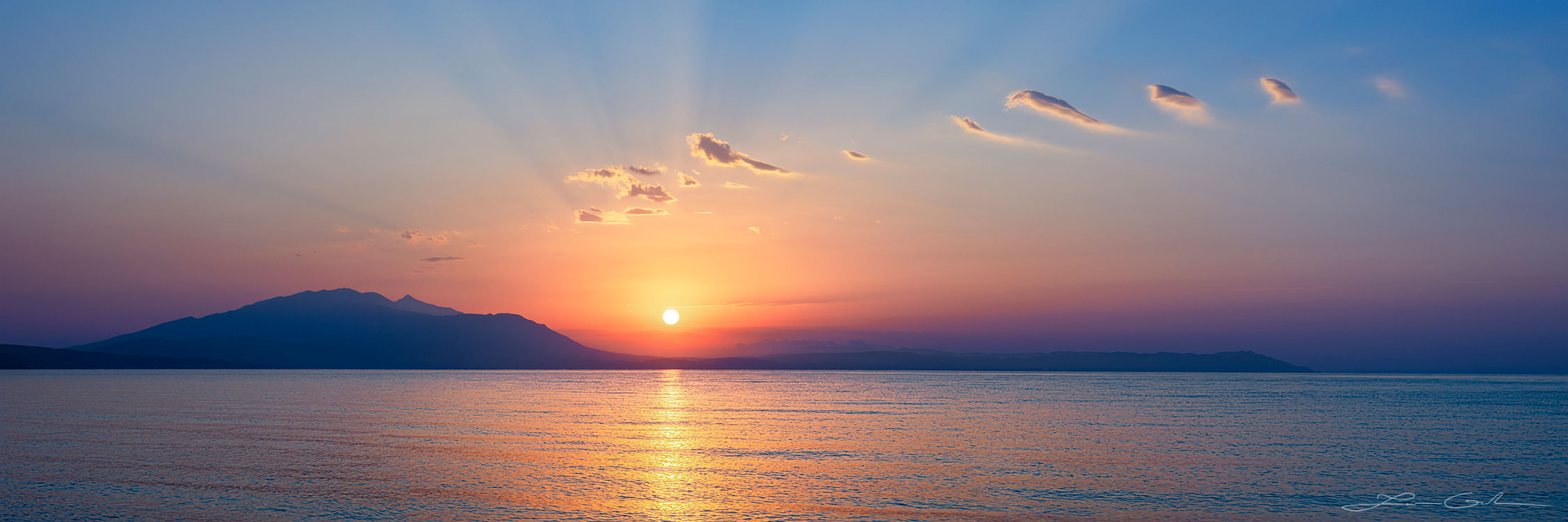 The sun rising above a mountain horizon and a sea gulf, Greece