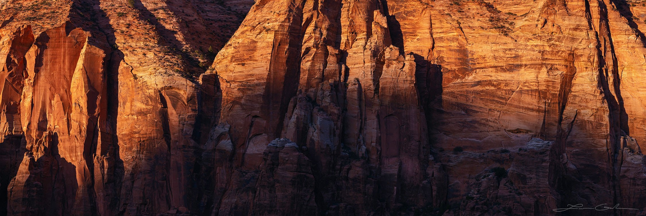 A vertical rock wall panorama of red stone illuminated by the sunset, Zion National Park