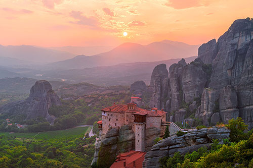 A Meteora monastery with a sunset in the background