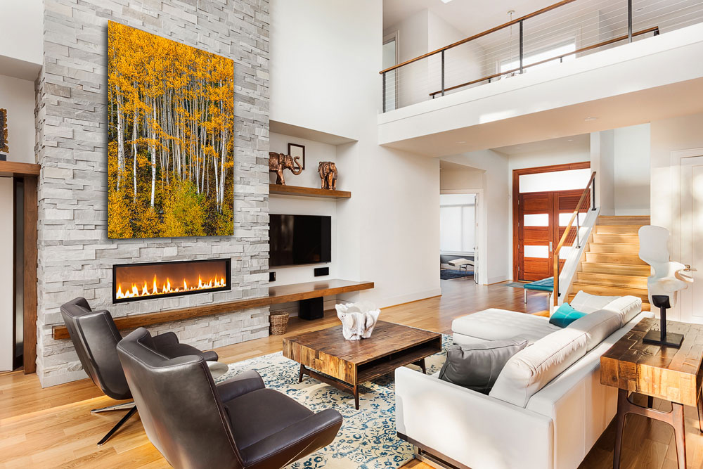 Big fine art print of golden aspen trees above a contemporary fireplace in a home interior