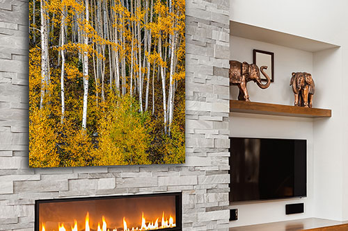 A beautiful print of yellow aspen trees on a stone wall above a modern fireplace interior - Small