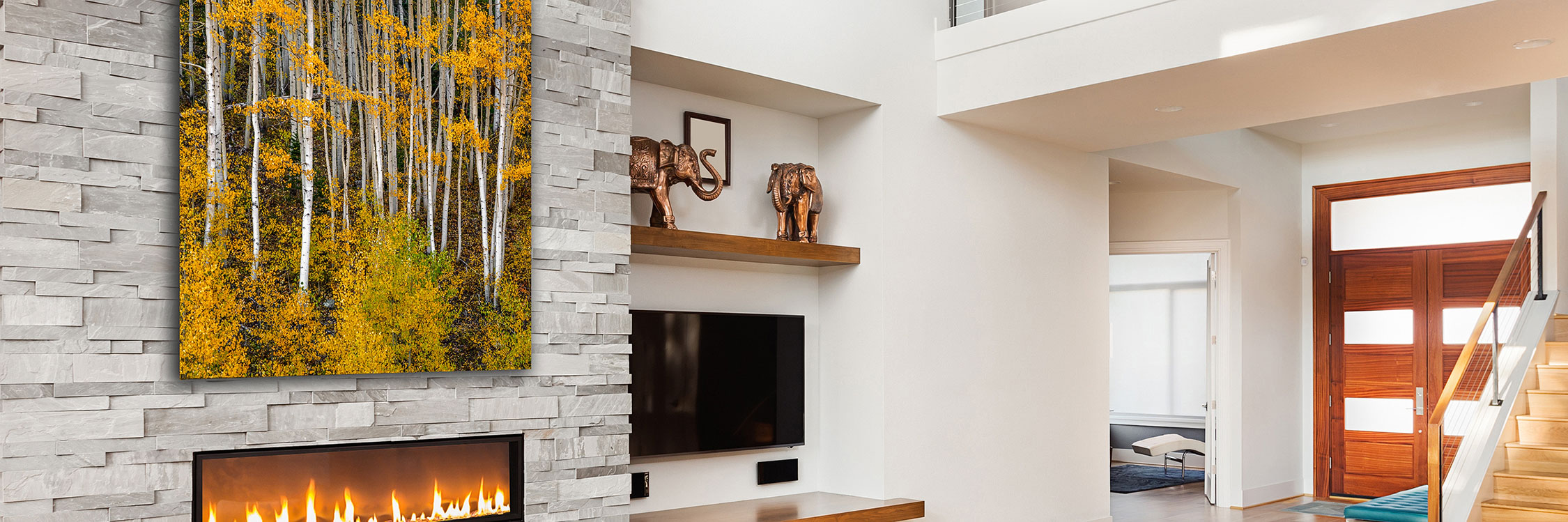 A beautiful print of yellow aspen trees on a stone wall above a modern fireplace interior