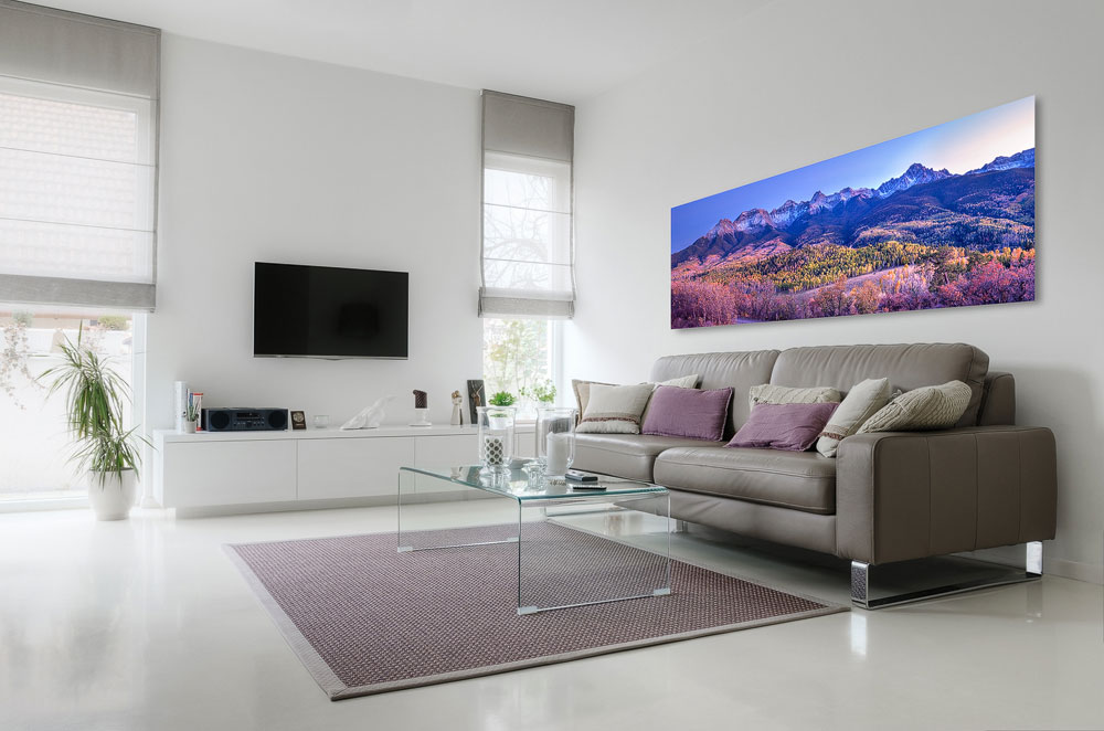 A panoramic print of mountains and fall colors above a contemporary sofa and interior