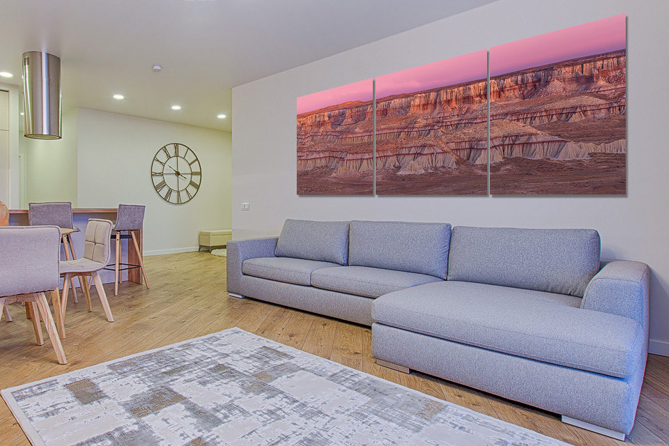 A beautiful triptych print of a desert canyon on a wall above a gray sofa interior