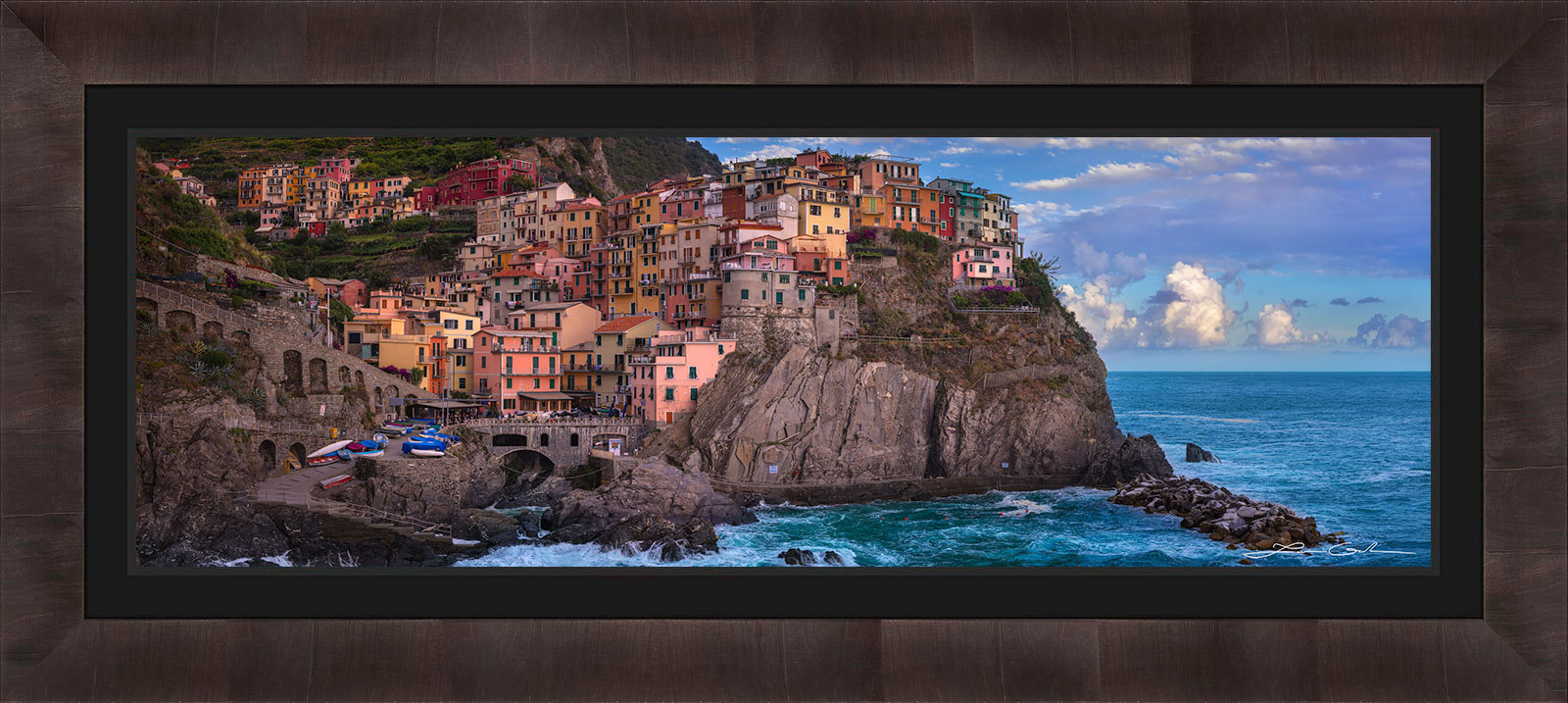 A framed print of Manarola, Italy with colorful houses on a sea shore