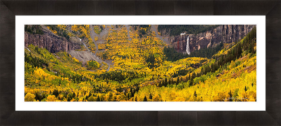 A mountain valley with lots of yellow aspens and a waterfall, framed in a dark frame