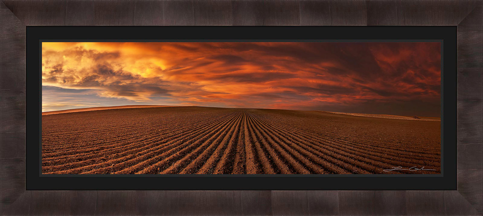 A framed print of a field with dramatic red clouds and skies