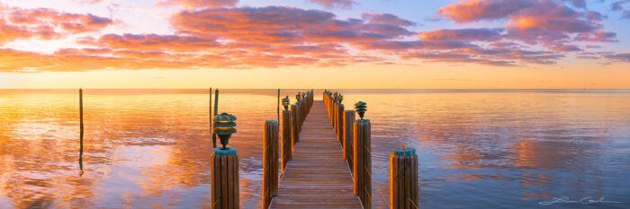 Wooden dock, or pier, extending into the ocean during an orange sunrise with pink clouds in the sky - Florida Keys - a fine art photograph by Lazar Gintchin.