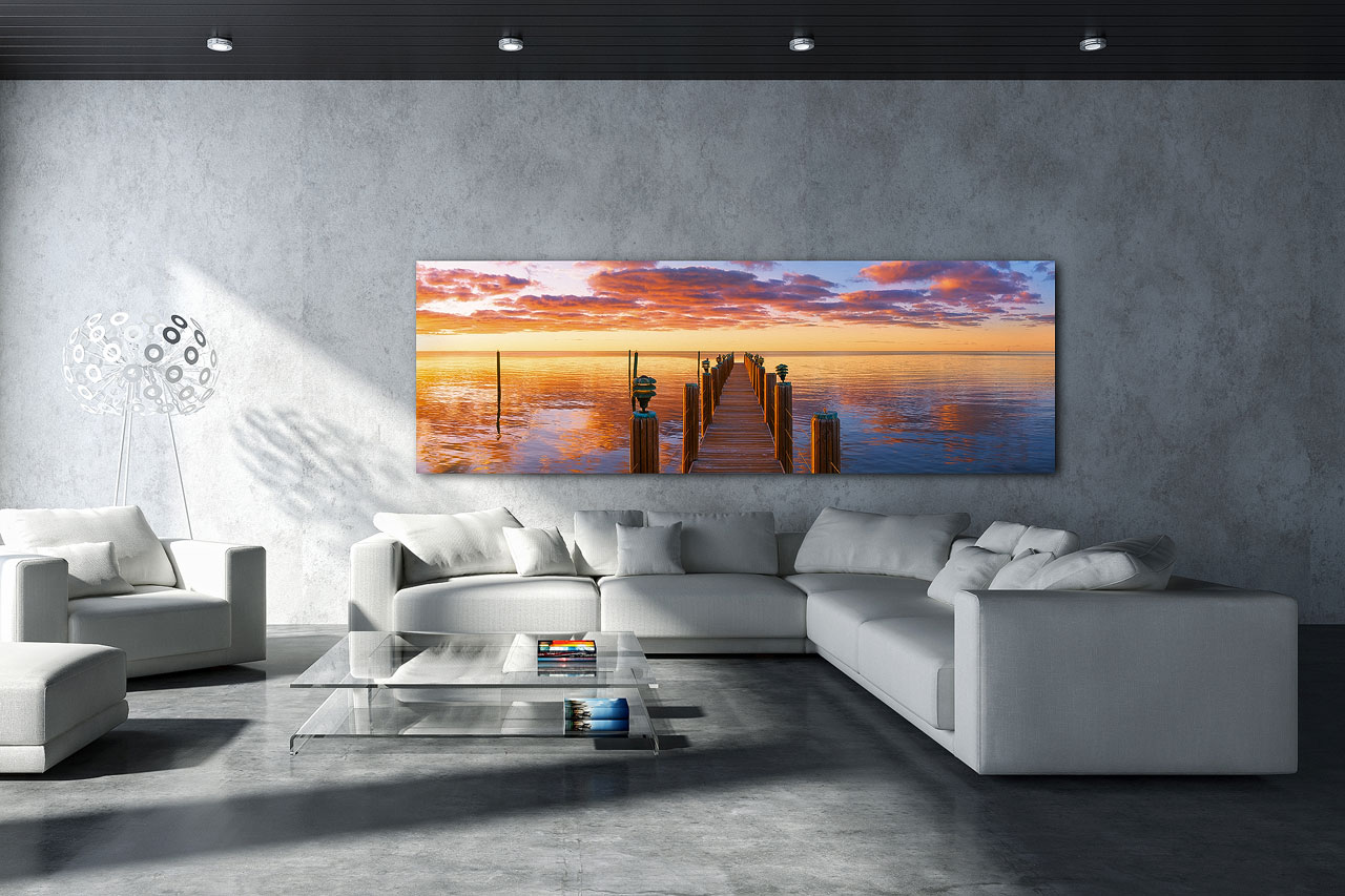 Interior design with fine art photography showcases a large panoramic wall art print of a wooden jetty / pier, extending into the ocean at sunrise. inside a modern living room - Gintchin Fine Art