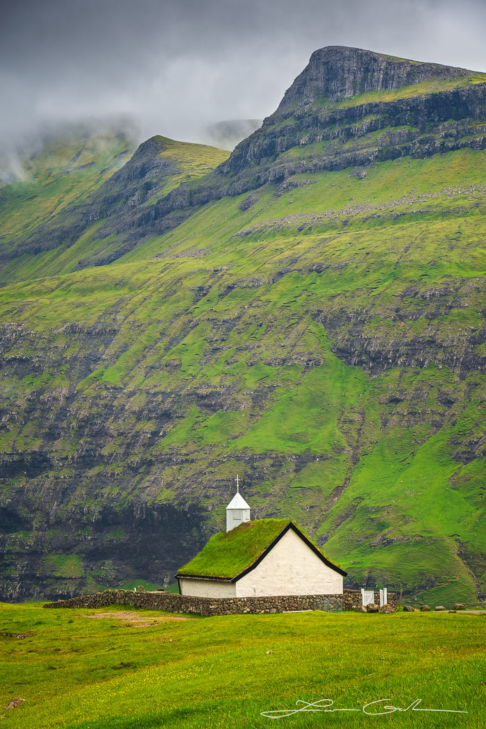 A beautiful church at the base of green lush mountains - Faroe Islands - Gintchin Fine Art