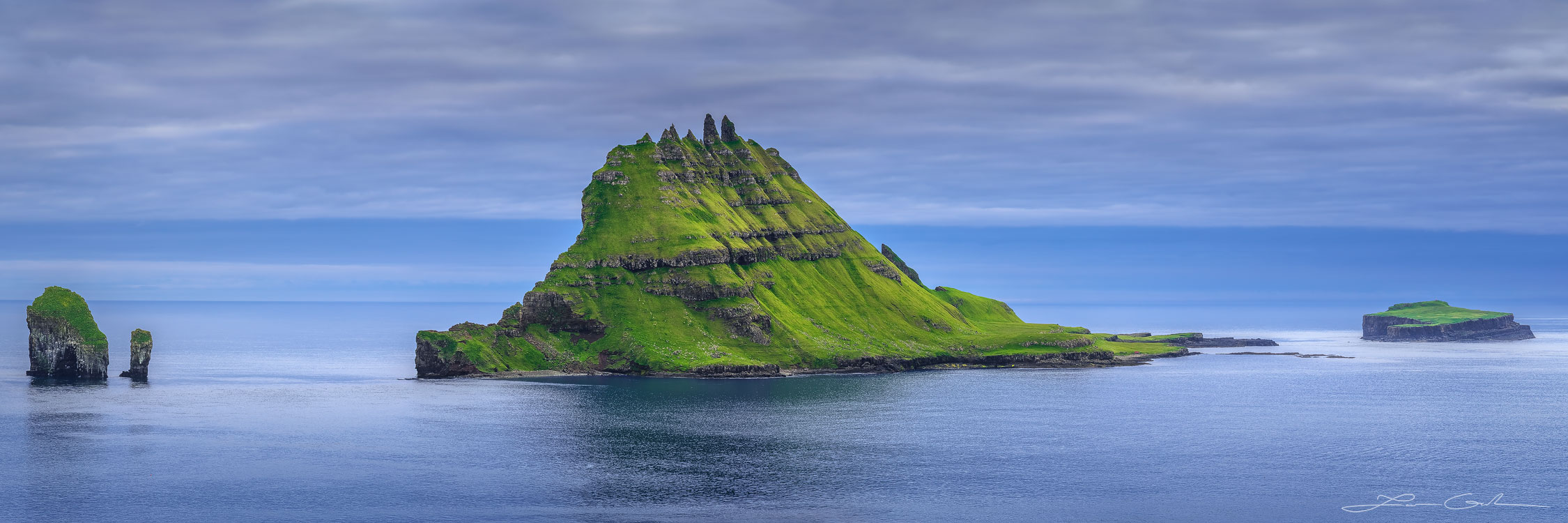 A lush green mountain island with sharp peaks in the middle of the ocean - Faroe Islands - Gintchin Fine Art