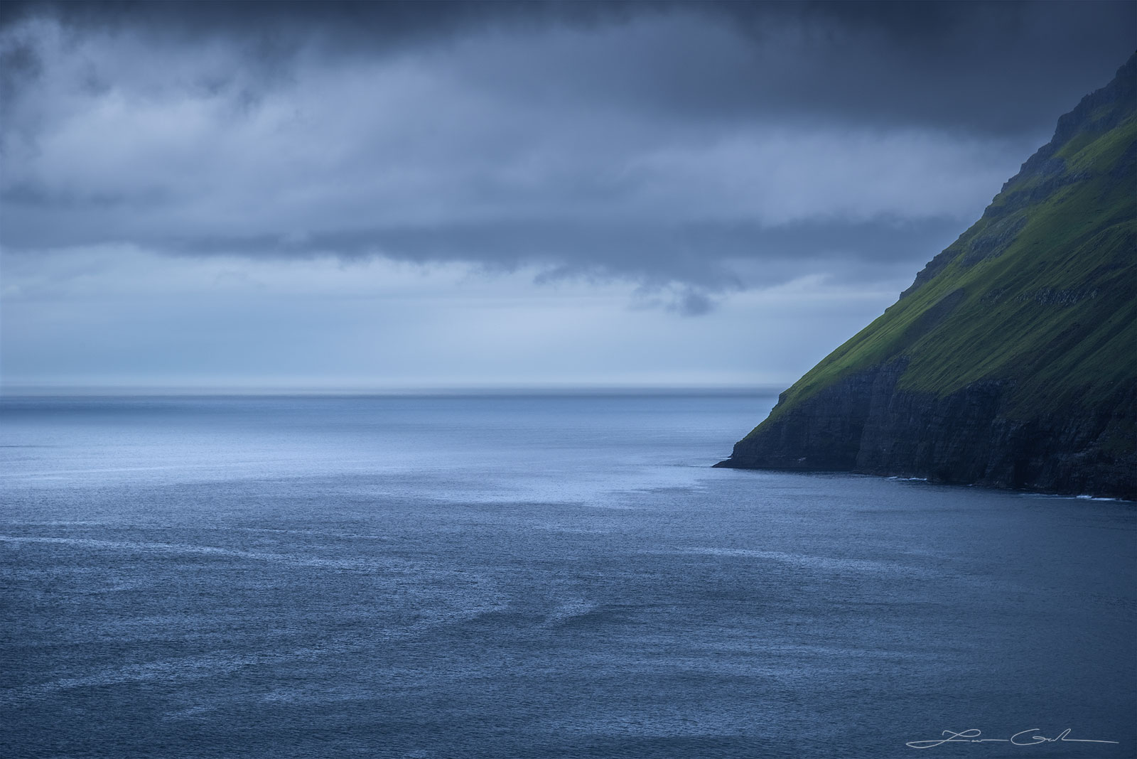 A steep ocean coast meets the water on a cloudy day - Faroe Islands - Gintchin Fine Art