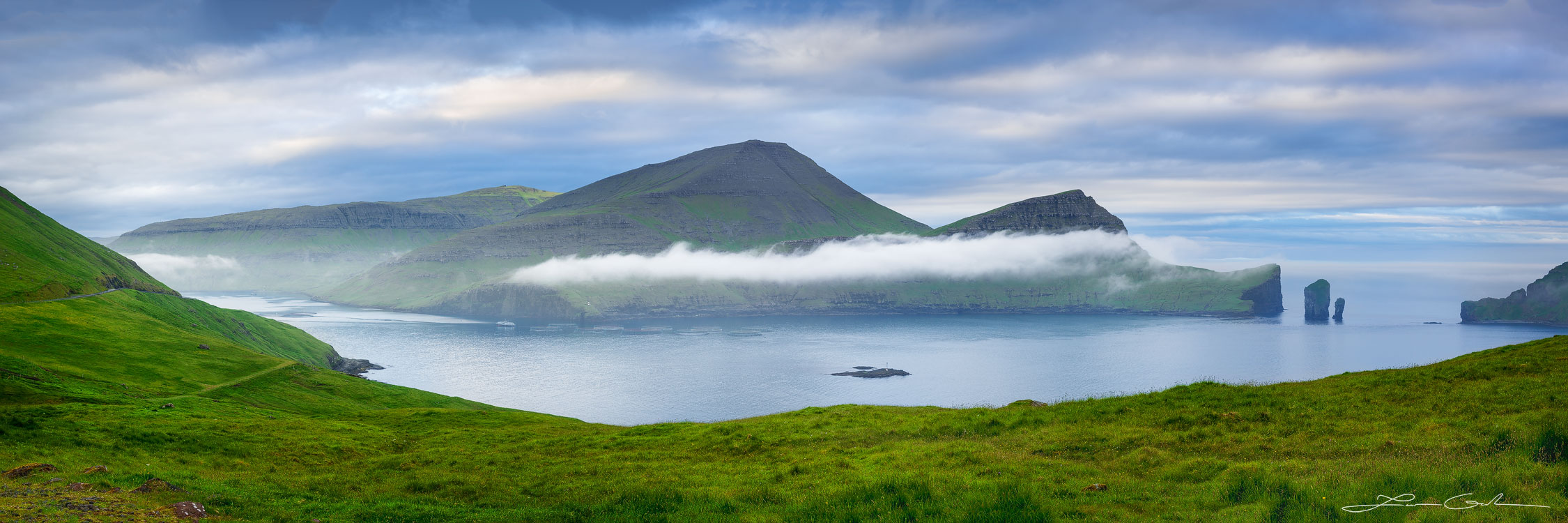 A beautiful fjord surrounded by green lush mountains and some fog - Faroe Islands - Gintchin Fine Art