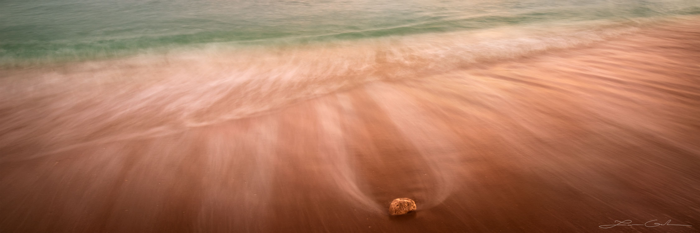 A single rock on a soft sandy shore with a receding wave abstract photograph - Gintchin Fine Art