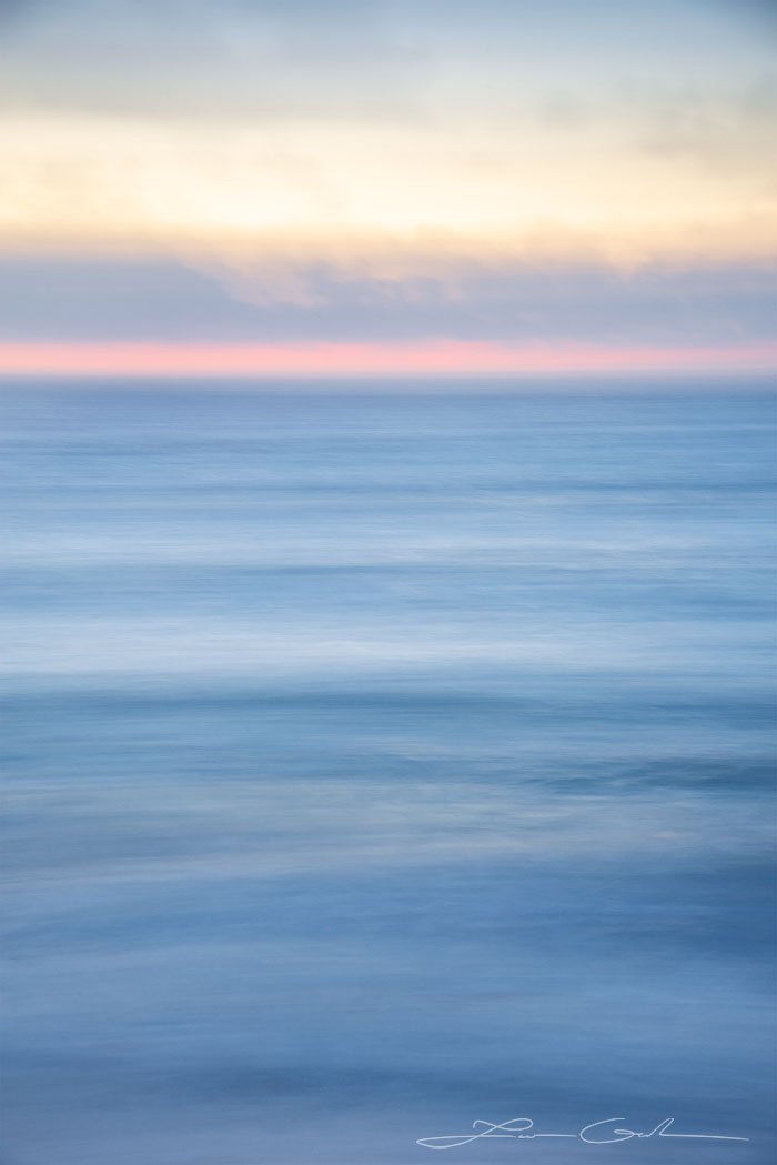 A soft blue ocean abstract photo with a band of pink above the horizon sunrise - Gintchin Fine Art