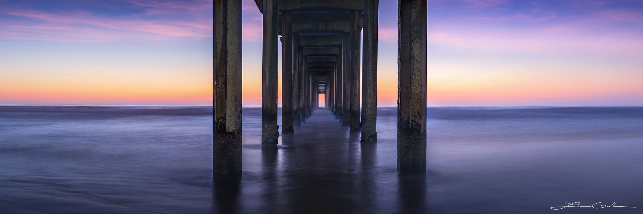 A twilight pier with beautiful sunset light and slow motion ocean water in California - Gintchin Fine Art