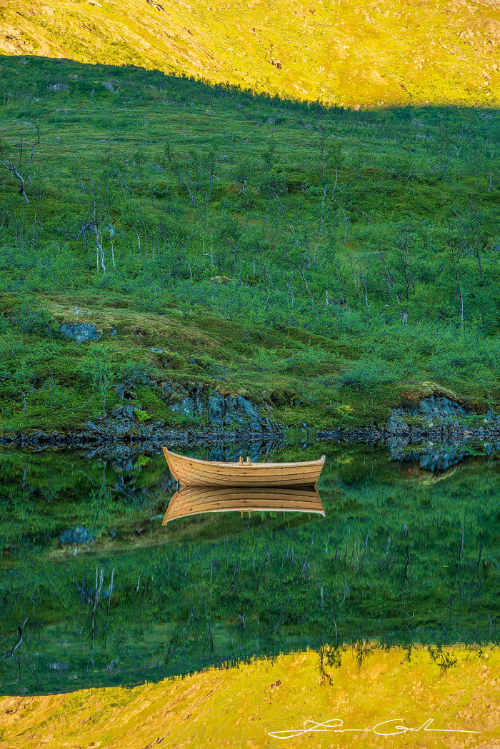 A boat in a calm mountain lake with beautiful reflection at sunrise - Gintchin Fine Art