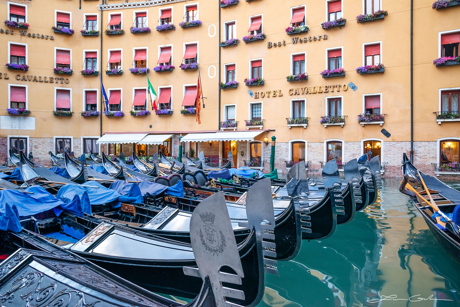 Many gondola boats parked in front of a hotel in Venice, Italy - Gintchin Fine Art