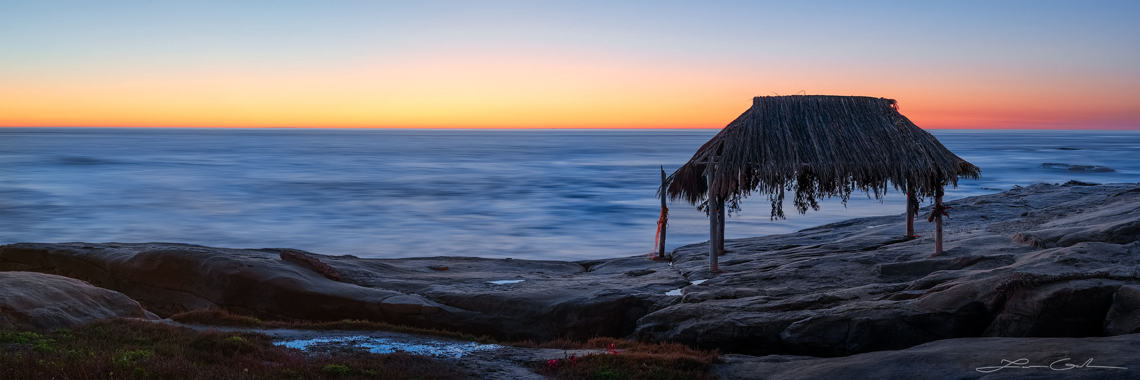 A slow motion ocean panorama with a rocky shore and a beautiful gazebo after sunset with orange colors in the sky near La Jolla, California - Gintchin Fine Art