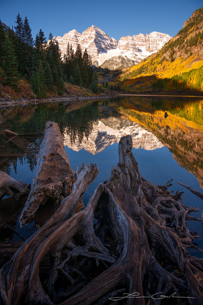 A vertical shot of the Maroon Bells mountains, near Aspen, Colorado, reflected in the calm water of Maroon Lake with beautiful fall colors and fresh snow - Gintchin Fine Art