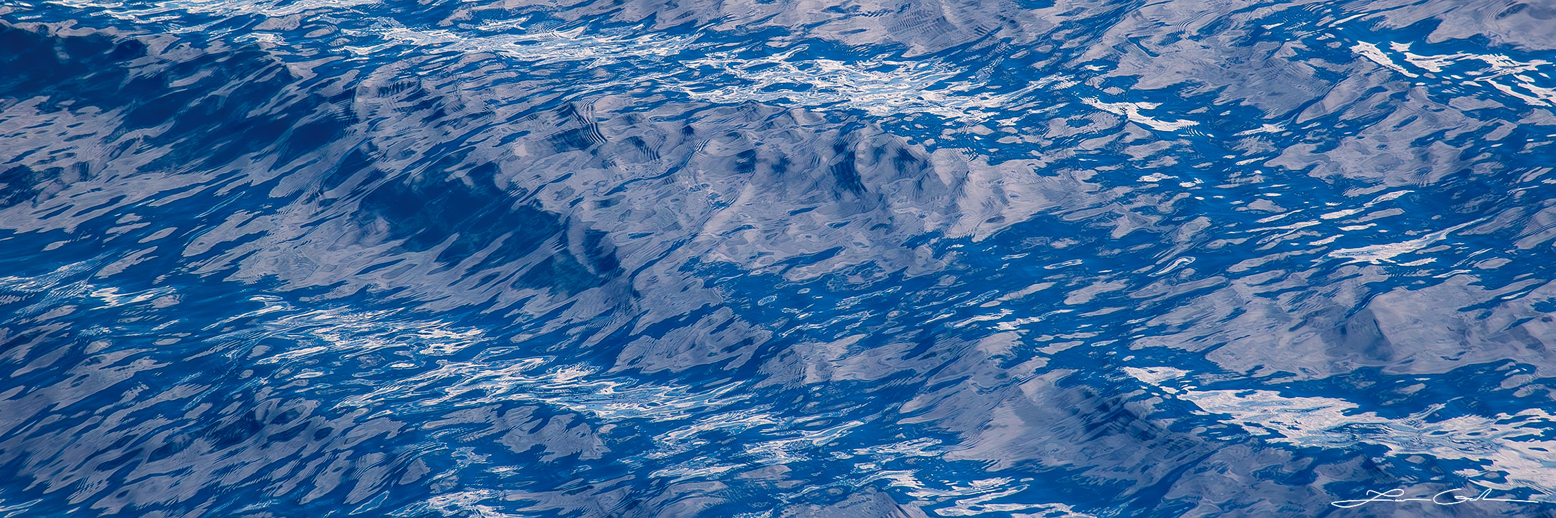 Panoramic fine art photography closeup displaying the hypnotic indigo color and gentle ripple texture of Maui's ocean water - Gintchin Fine Art.