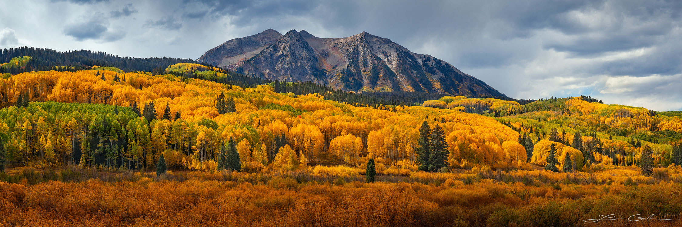 Rich fall colors in Colorado - Panoramic view of a mountain range with vibrant aspen trees displaying rich autumn foliage, capturing the beauty of fall in Colorado's rich fall colors.- Gintchin Fine Art