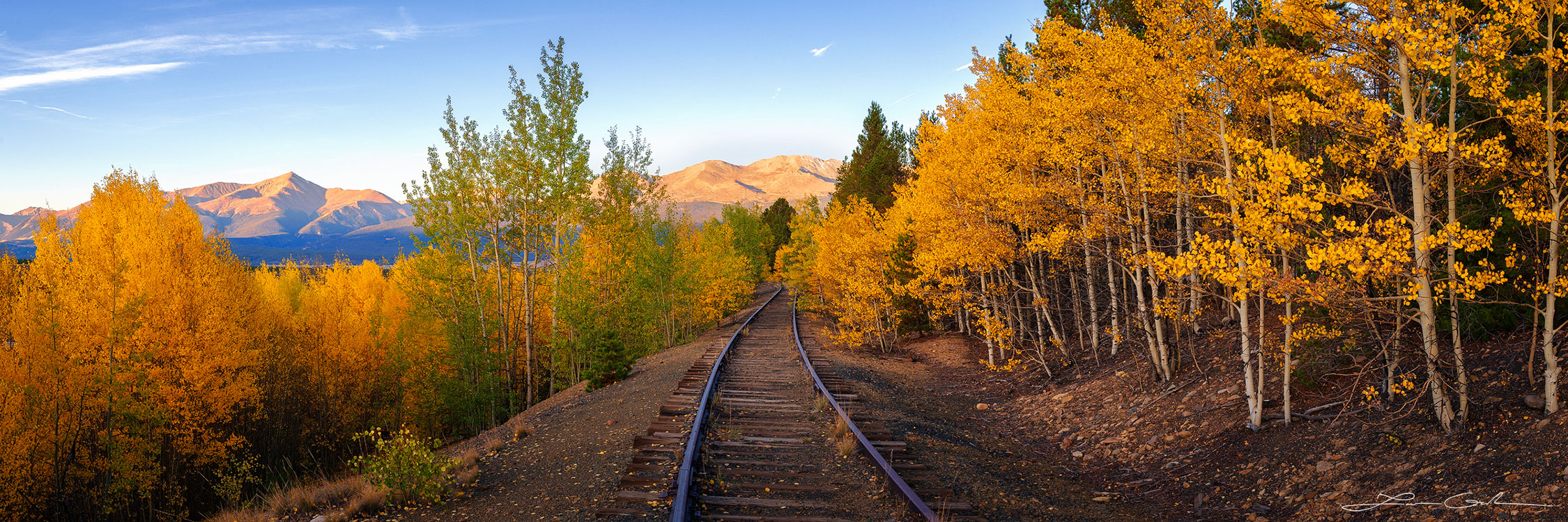 Mountain Railroad Fall Colors: Abandoned railway cutting through vibrant aspen forest with Mount Elbert in the distance. Serene early morning scene capturing the essence of autumn colors and Colorado's natural beauty. - Gintchin Fine Art