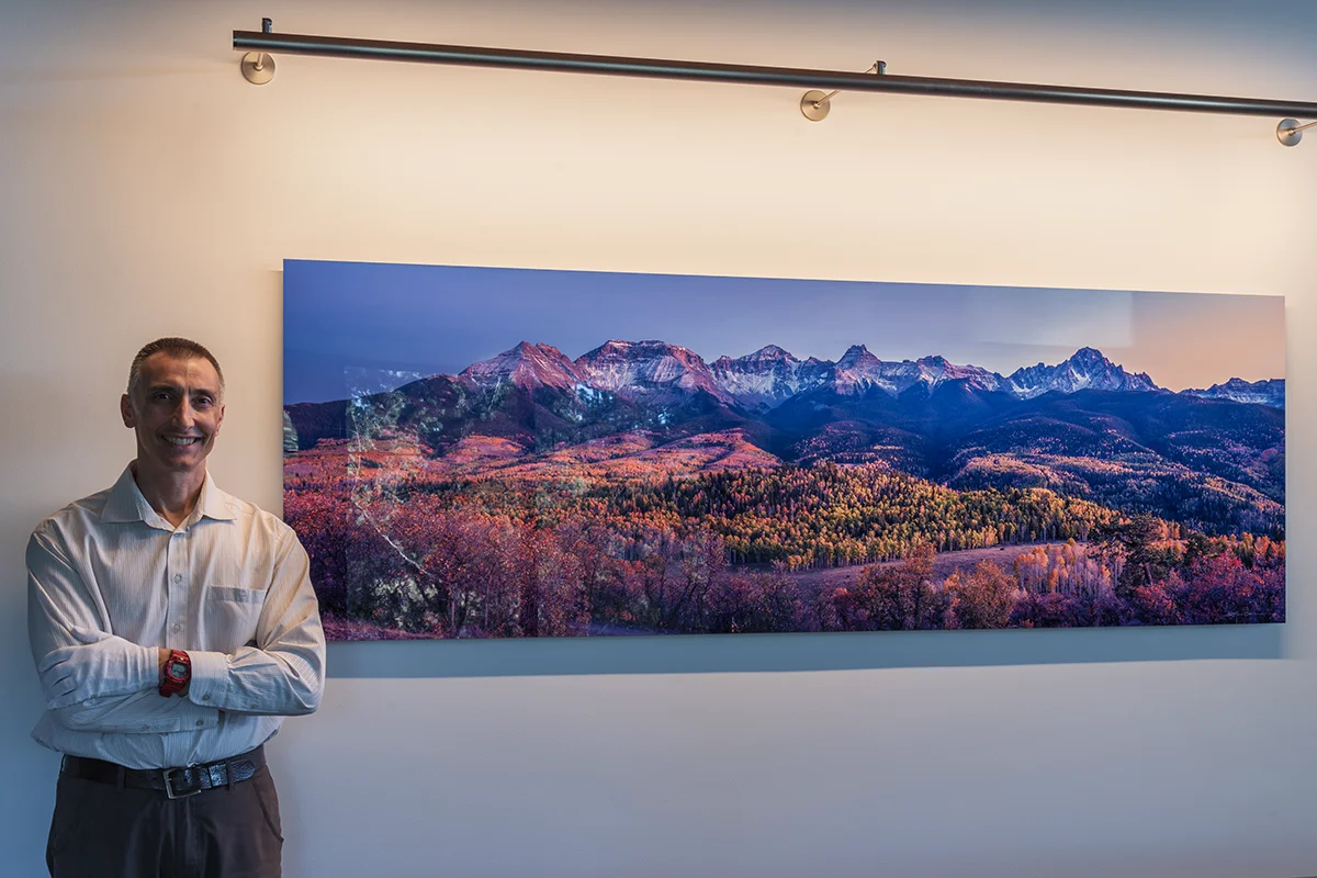 Lazar Gintchin standing next to a massive Colorado print, mounted on a wall in a customer home. - Gintchin Fine Art