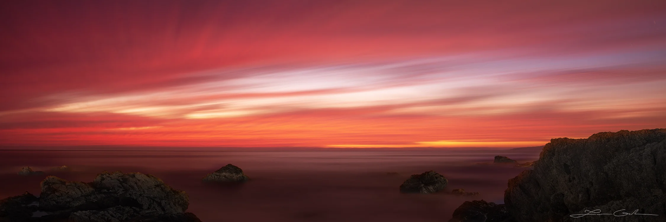 Fine art photo print of a dramatic sunset seascape along the Pacific Coast of Mexico, featuring vibrant hues of red, orange, and purple over a tranquil ocean with rocky outcrops. - Gintchin Fine Art