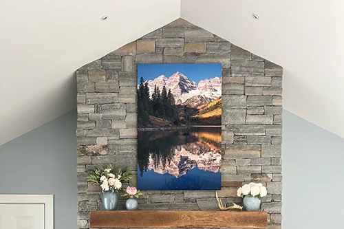 A metal print of Maroon Bells, Colorado on a stone wall fireplace - - Gintchin Fine Art