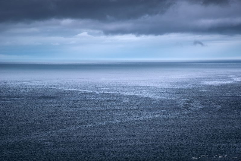 Ocean light glowing above the ocean water with a cloudy sky - Faroe Islands - Gintchin Fine Art