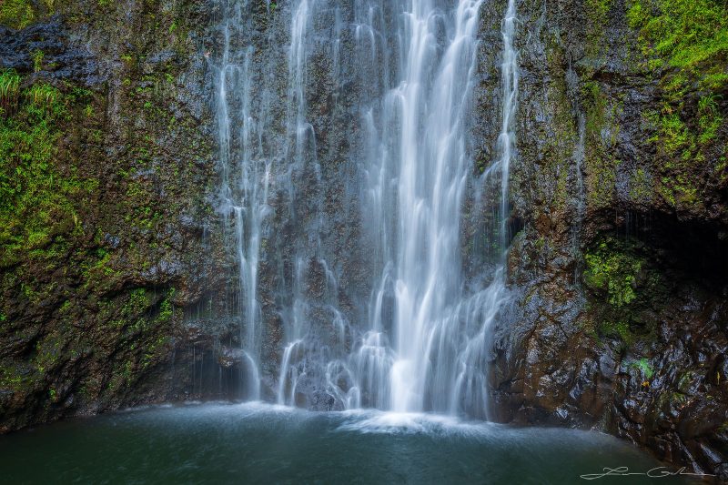 Slow motion photo of a gentle waterfall flowing down a moss-covered cliff into a natural pool in Maui, Hawaii - Gintchin Fine Art