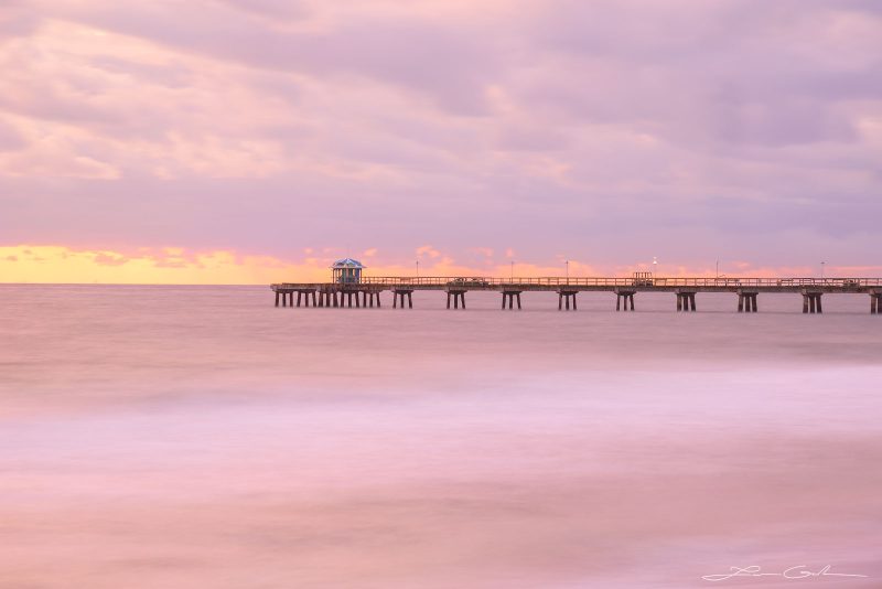 A pink colored ocean and clouds with a pier in Florida - Gintchin Fine Art
