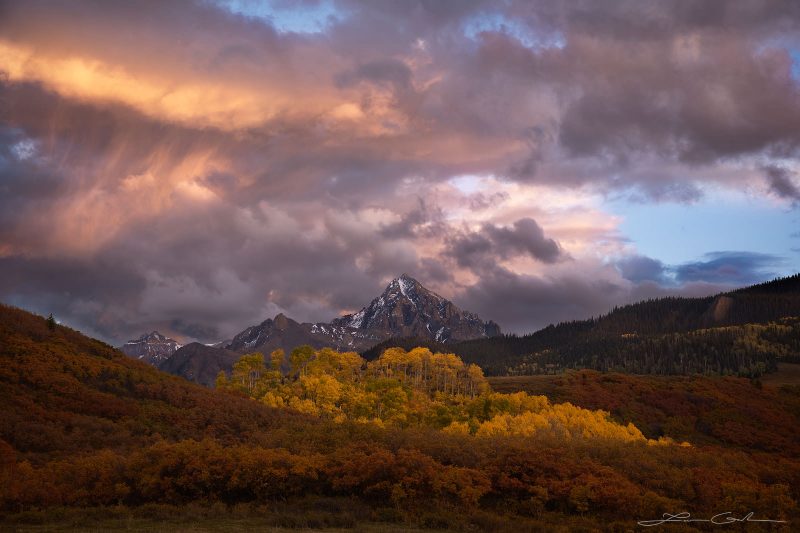 A beautiful mountain sunset in Colorado with orange clouds, Mt Sneffels, yellow aspens, and orange oaks