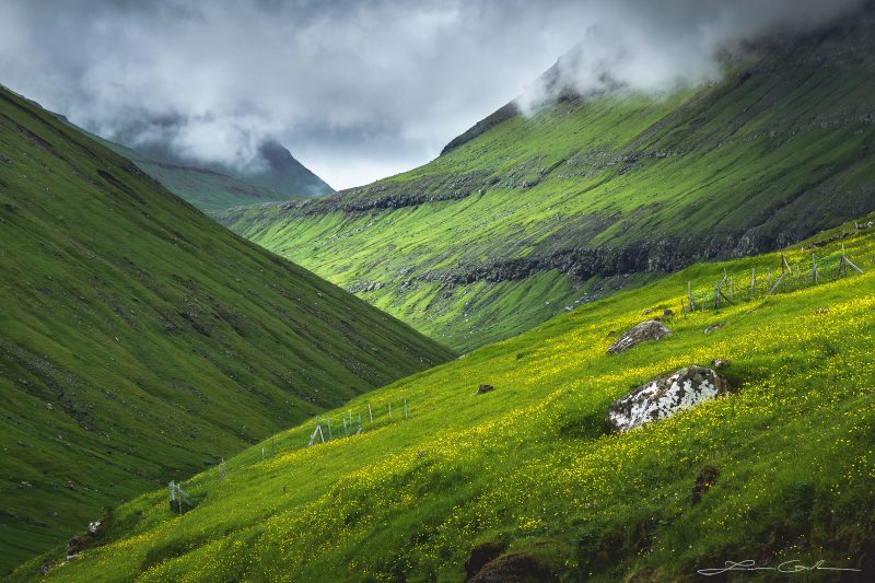 A mountain valley with green grass slopes and beautiful light, which looks like hobbit land - Faroe Islands - Gintchin Fine Art