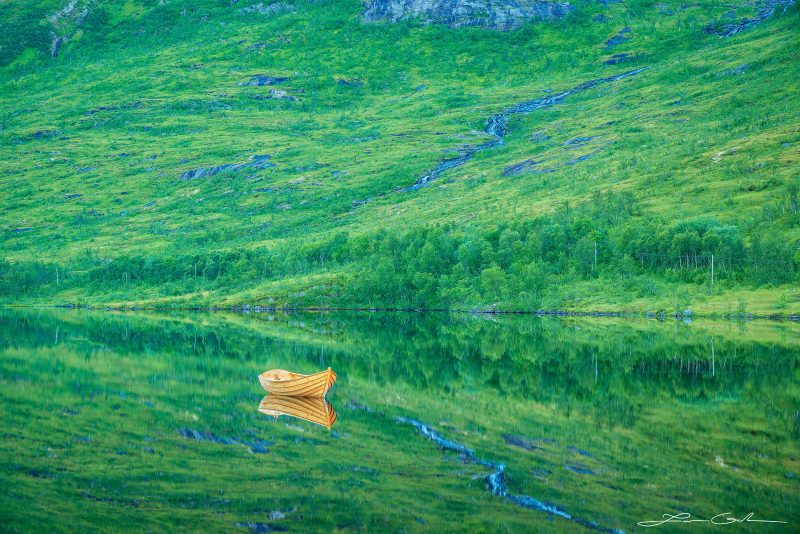 A wood boat on a lake with perfect reflection in Senja, Norway - Gintchin Fine Art
